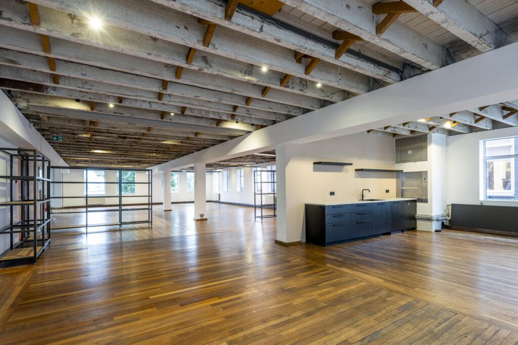 Ruim, industrieel kantoorinterieur aan de De Ruijterkade met open indeling, houten vloer en moderne kitchenette.